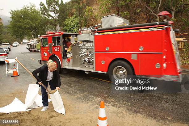 Resident at the base of the San Gabriel Mountains, which were scorched and denuded by the 250-square-mile Station fire, fill sandbags as they prepare...