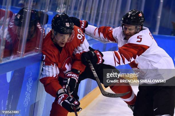 Canada's Chay Genoway checks Switzerland's Gaetan Haas in the men's preliminary round ice hockey match between Switzerland and Canada during the...