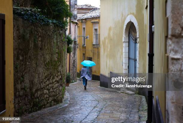 sicily: rainy-windy day in baroque town; woman with blue umbrella - ragusa sicily stock pictures, royalty-free photos & images