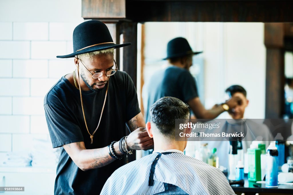 Barber trimming clients bangs during hair cut in barber shop