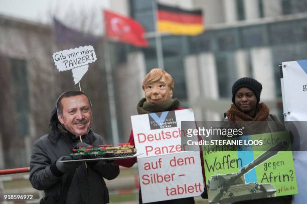 Activists of the human rights organization "Gesellschaft fuer bedrohte Voelker" wear masks of German Chancellor Angela Merkel and Turkish President...