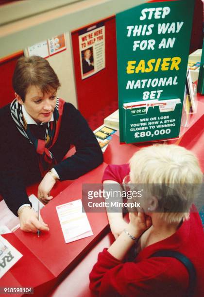 Chris Hudson, mangers of Ladbrokes in the Bigg Market, gives out last minute tips to Grand National Punter Emma Walker, 2nd April 1997.