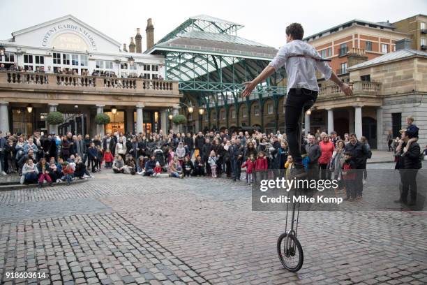 Street performer with a tall unicycle thrills the gathered crowd with his performance in Covent Garden, London, England, United Kingdom.