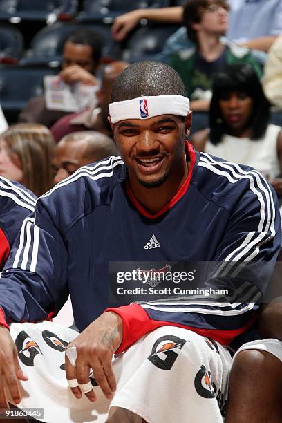 Josh Smith of the Atlanta Hawks looks on with a smile from the bench during the preseason game against the New Orleans Hornets at Philips Arena on...