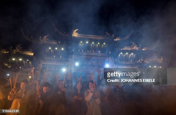 People pray with incense sticks to celebrate the Lunar New Year, marking the Year of the Dog, at the Longhua temple in Shanghai early February 16,...