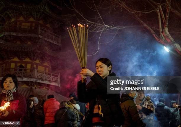 People pray with incense sticks to celebrate the Lunar New Year, marking the Year of the Dog, at the Longhua temple in Shanghai early February 16,...