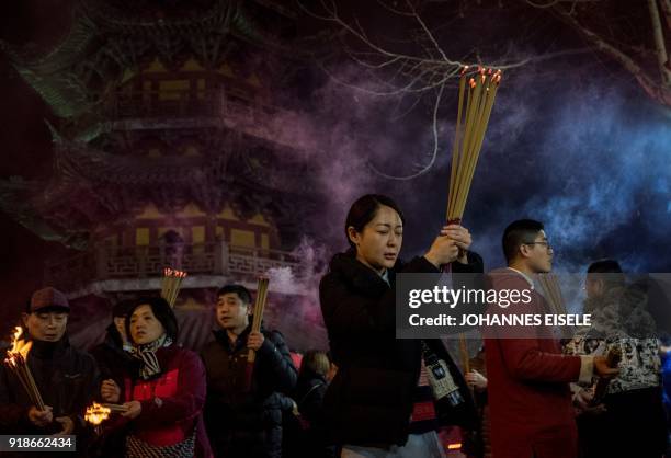 People pray with incense sticks to celebrate the Lunar New Year, marking the Year of the Dog, at the Longhua temple in Shanghai early February 16,...