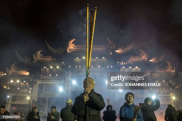 People pray with incense sticks to celebrate the Lunar New Year, marking the Year of the Dog, at the Longhua temple in Shanghai early February 16,...