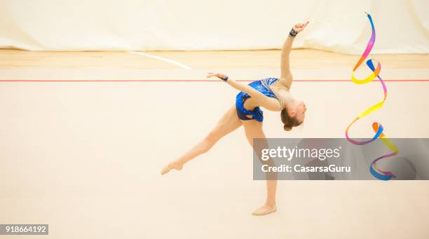 teenage rhythmic gymnastics athlete doing ribbon routine - ribbon routine rhythmic gymnastics stock pictures, royalty-free photos & images