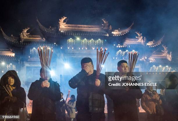 People pray with incense sticks to celebrate the Lunar New Year, marking the Year of the Dog, at the Longhua temple in Shanghai early February 16,...