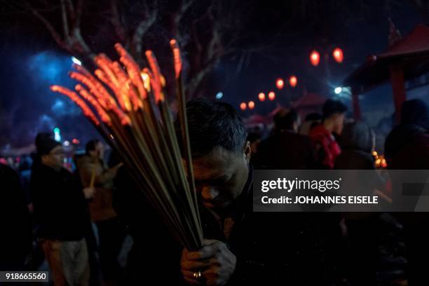 People pray with incense sticks to celebrate the Lunar New Year, marking the Year of the Dog, at the Longhua temple in Shanghai early February 16,...