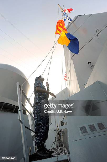 In this photo provided by the U.S. Navy, Quartermaster Seaman Jason Lightburn raises the international call sign of the amphibious transport dock...