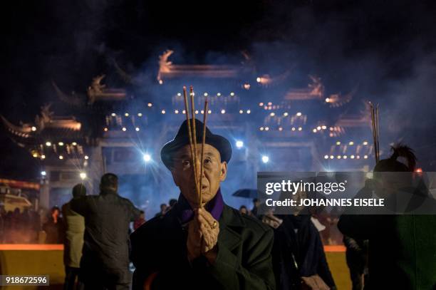 People pray with incense sticks to celebrate the Lunar New Year, marking the Year of the Dog, at the Longhua temple in Shanghai early February 16,...