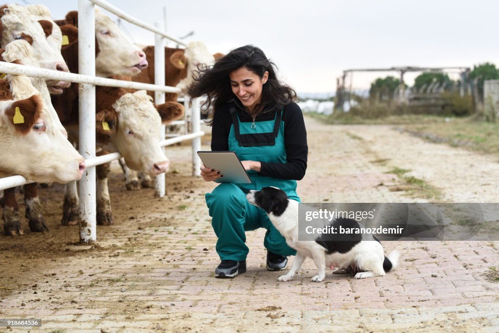 Jeune agricultrice avec vaches et son chien