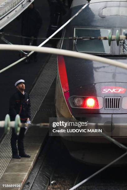 Platform staff looks up as he prepares to give the departing signal to a high speed TGV train at the Gare de l'Est railway station on Febuary 15,...