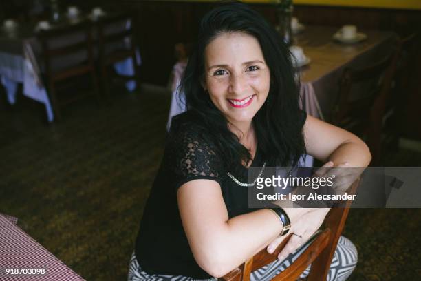 mature latin woman at cafe - moving down to seated position stock pictures, royalty-free photos & images