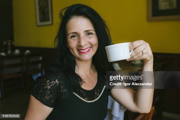 mature latin woman at cafe - moving down to seated position stock pictures, royalty-free photos & images