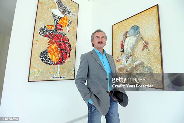 Painter Akmal Nur poses with his works during the Akmal Nur Exhibition opening at The Center of National Arts on October 13, 2009 in Tashkent,...