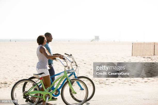 在海灘上推自行車的情侶談話 - santa monica 個照片及圖片檔