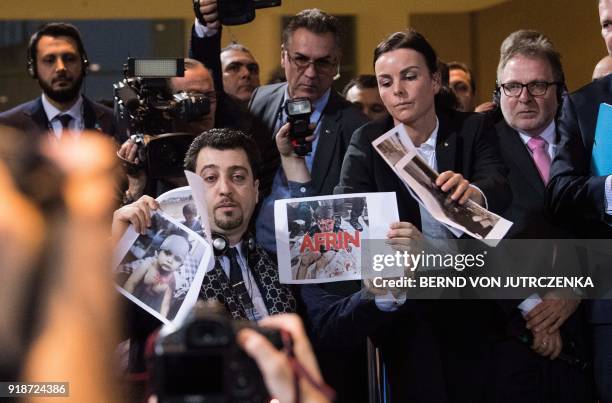 Journalist with a Kurdish news site holds up pictures of injured children during a press conference of the German Chancellor with the Turkish Prime...