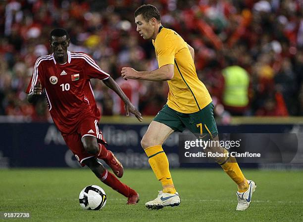 Brett Emerton of Australia keeps the ball away from Fawzi Bahir of Oman during the Asian Cup Group B qualifying match between the Australian...