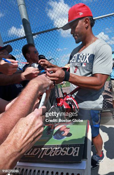 Boston Red Sox shortstop Xander Bogaerts signs some autographs for fans after practice, with one holding out an old copy of Baseball America that has...