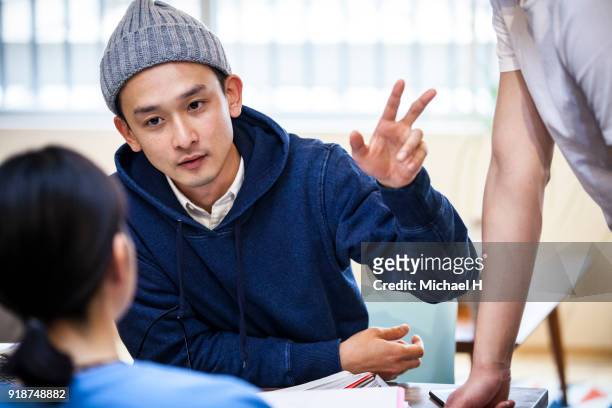 young businessman speaking in an informal meeting - navy blue interior stock pictures, royalty-free photos & images