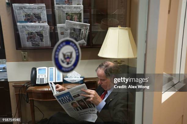 Sen. Doug Jones reads a copy of The Hill newspaper prior to a news conference February 15, 2018 at the Capitol in Washington, DC. The so-called...