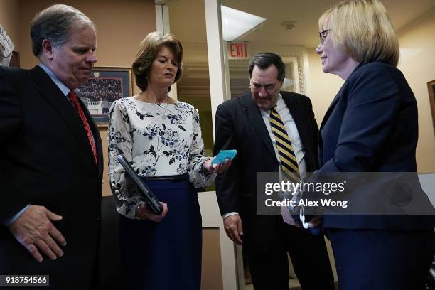 Sen. Lisa Murkowski reads from a piece of paper as Sen. Doug Jones , Sen. Joe Donelly and Sen. Maggie Hassan listen prior to a news conference...