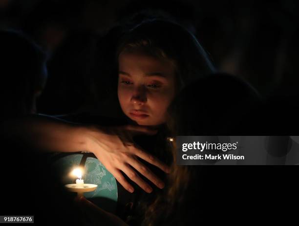 Young girl clutches a friend during candlelight vigil for victims of the mass shooting at Marjory Stoneman Douglas High School yesterday, at Pine...