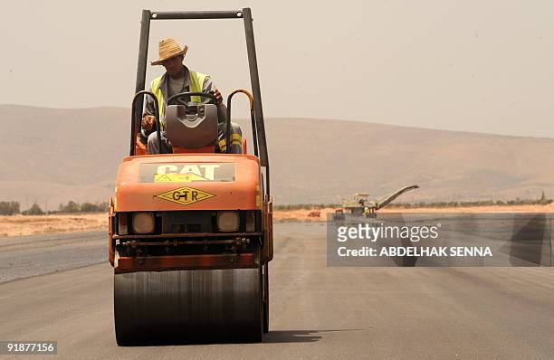 Moroccan worker drives a Caterpillar asphalt compactor at construction site on July 21 of Oujda airport. French Colas and Moroccan GTR consortium won...