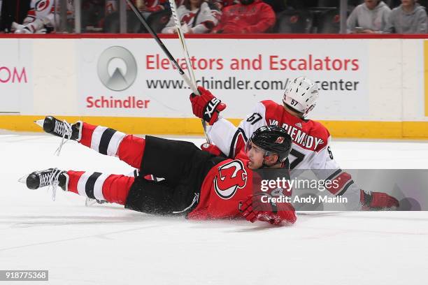 Miles Wood of the New Jersey Devils and Trevor van Riemsdyk of the Carolina Hurricanes get tangled up during the game at Prudential Center on...