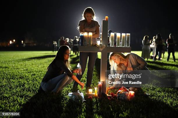 Maria Reyes, Stacy Buehler and Tiffany Goldberg light candles around a cross as they attend a candlelight memorial service for the victims of the...