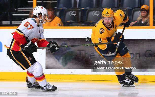 Filip Forsberg of the Nashville Predators tries to control a bouncing puck in front of Michael Frolik of the Calgary Flames during the first period...
