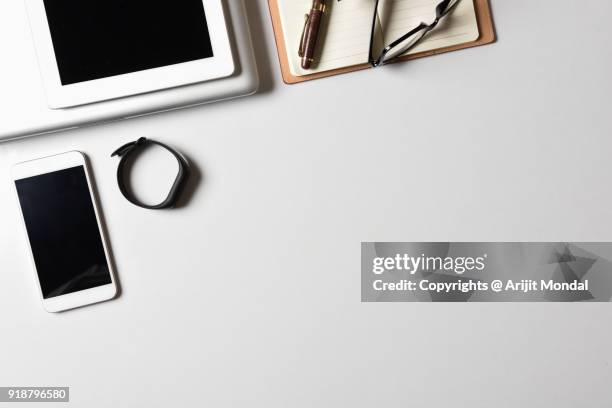 fitness band on office desk with laptop, tablet and smartphone directly above white background copy space - desk aerial view stock pictures, royalty-free photos & images