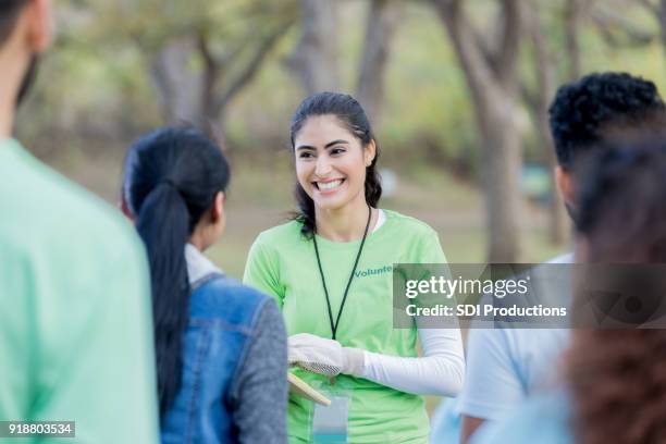 young woman stands outside and leads volunteer training session - park service stock pictures, royalty-free photos & images
