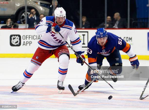 Peter Holland of the New York Rangers and Casey Cizikas of the New York Islanders chase down a loose puck during the third period at Barclays Center...