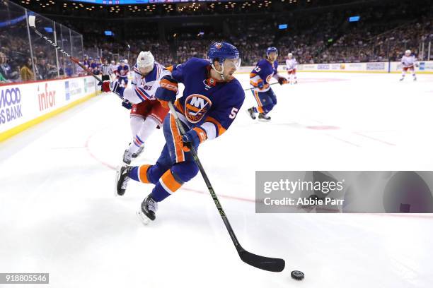 Adam Pelech of the New York Islanders skates with the puck against Rick Nash of the New York Rangers in the third period during their game at...