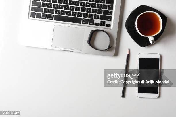 smartphone with fitness tracker, green tea and laptop on white office desk copy space - business tracker stock-fotos und bilder