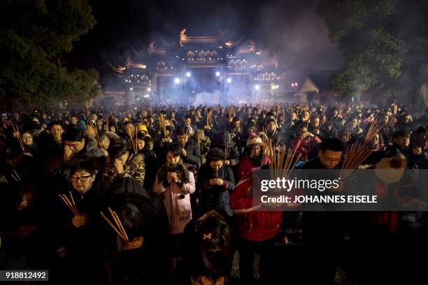 This picture taken late on February 15, 2018 shows people praying with incense sticks to celebrate the Lunar New Year, marking the Year of the Dog,...