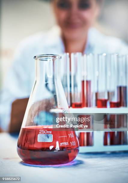 lab flask and test tubes with red liquid, scientist behind - volume fluid capacity stock pictures, royalty-free photos & images