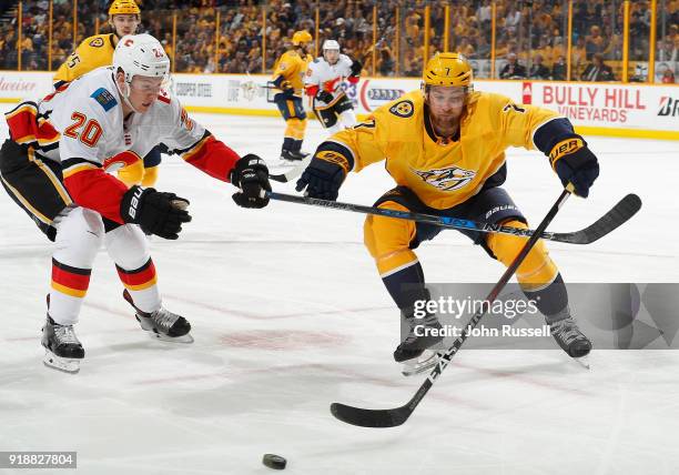 Curtis Lazar of the Calgary Flames battles for the puck against Yannick Weber of the Nashville Predators during an NHL game at Bridgestone Arena on...