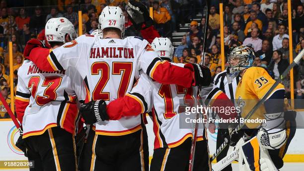 Sean Monahan, Michael Stone, and Johnny Gaudreau of the Calgary Flames celebrate a goal against goalie Pekka Rinne of the Nashville Predators during...