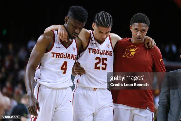 Bennie Boatwright of the USC Trojans gets helped off the court by team mates Chimezie Metu and Harrison Henderson after injuring knee against Oregon...