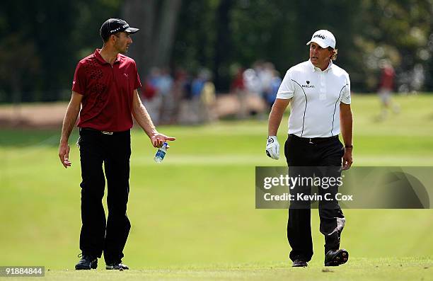 Geoff Ogilvy of Australia and Phil Mickelson talk during the first round of THE TOUR Championship presented by Coca-Cola, the final event of the PGA...