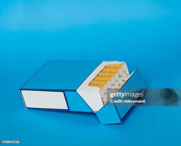 cigarette box and cigarettes on blue background - cigarette filter stock pictures, royalty-free photos & images