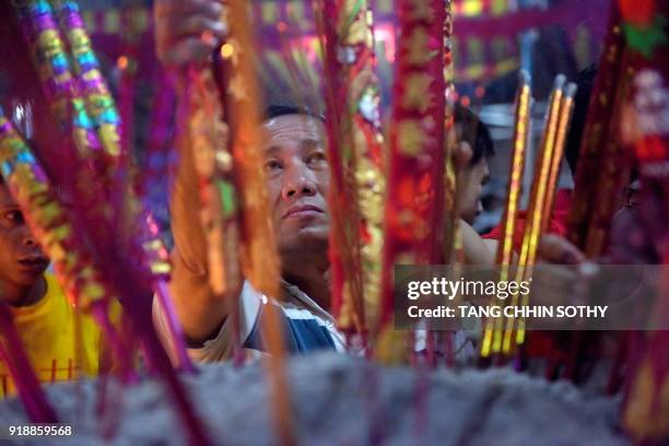 Cambodian-Chinese man places a stick of incense into an urn at a temple to mark the start of the Lunar New Year in Kandal on February 16, 2018. While...