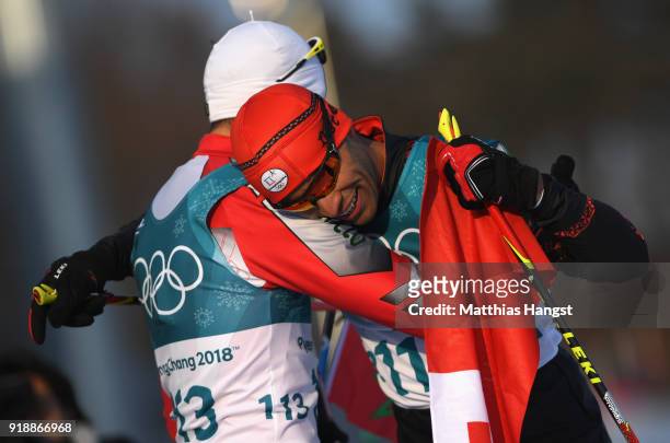 Pita Taufatofua of Tonga reacts with Samir Azzimani of Morocco after crossing the finish line during the Cross-Country Skiing Men's 15km Free at...