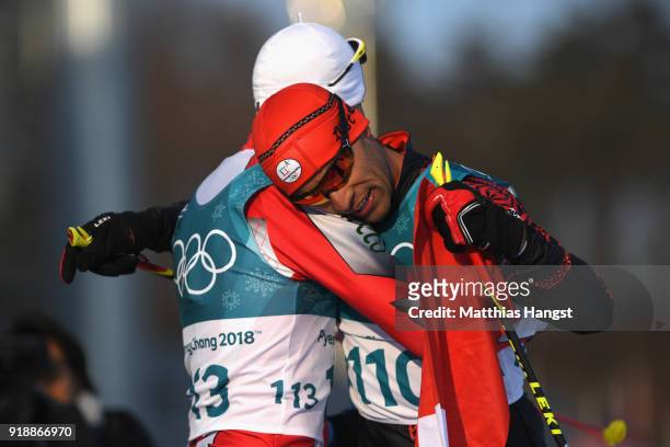 Pita Taufatofua of Tonga reacts with Samir Azzimani of Morocco after crossing the finish line during the Cross-Country Skiing Men's 15km Free at...