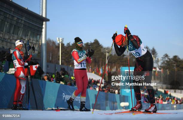 Pita Taufatofua of Tonga crosses the finish line as Kequyen Lam of Portugal and Samir Azzimani of Morocco look on during the Cross-Country Skiing...